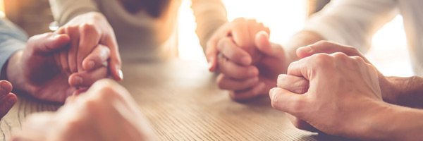 People hold hands while sitting at a table