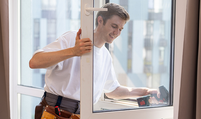 Contractor uses drill to install home window