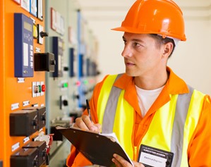 Engineer reads gauges on machinery in factory