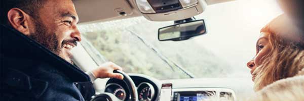 Man laughs at woman’s joke while driving