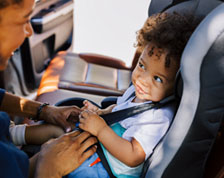 Parent buckles toddler into car seat