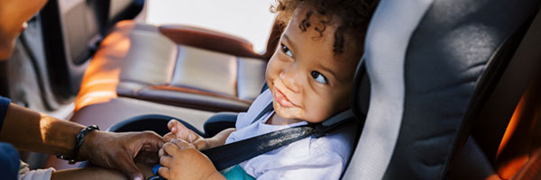Parent buckles toddler into car seat