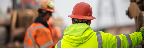 Construction workers stand at a distance