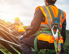 Construction worker wearing safety harness looks across rooftop