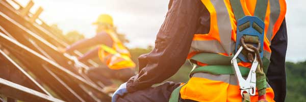 Construction worker wearing safety harness looks across rooftop