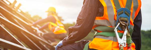 Construction worker wearing safety harness looks across rooftop