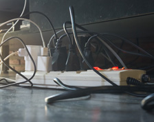 Several tangled cords plug into a power strip to support different electrical devices.