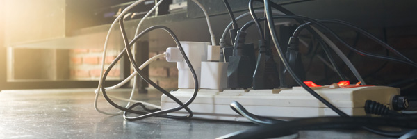 Several tangled cords plug into a power strip to support different electrical devices.