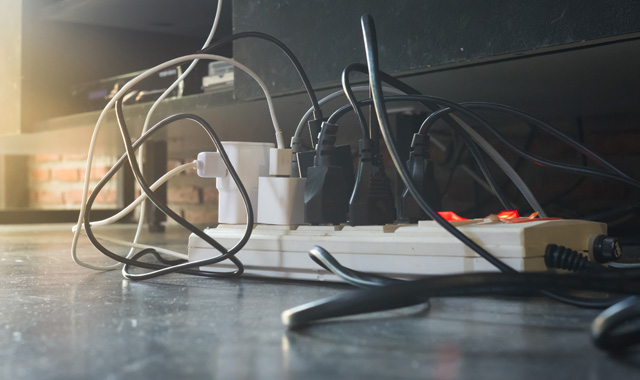 Several tangled cords plug into a power strip to support different electrical devices.
