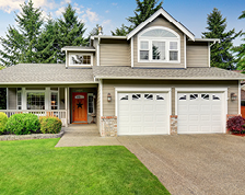 A taupe two story home with an orange front door, white window trim and a manicured lawn.