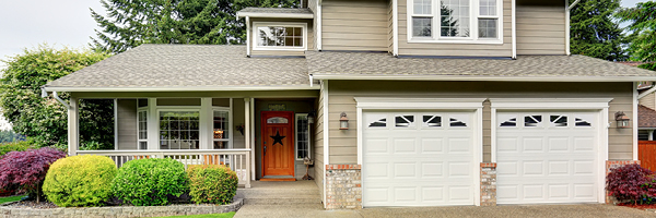 A taupe two story home with an orange front door, white window trim and a manicured lawn.
