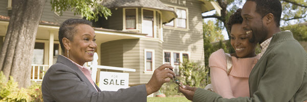 Realtor hands house keys to young couple