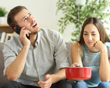 Man talks on phone while woman catches ceiling water leak in pot