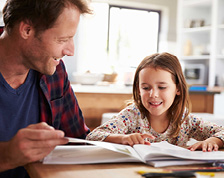 Father and daughter sitting at kitchen table, reviewing home emergency planning booklet