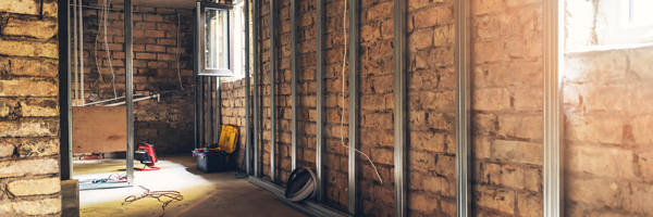 A basement with brick walls and metal supports against the walls and foundation.