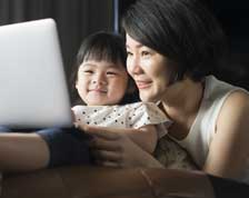 A grandmother and granddaughter look at a laptop together