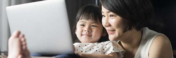 A grandmother and granddaughter look at a laptop together