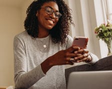 Woman uses smartphone and smiles inside her home