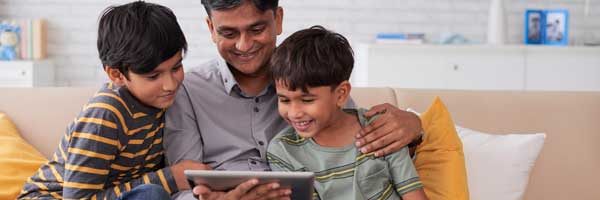Father and sons look at tablet computer while at home