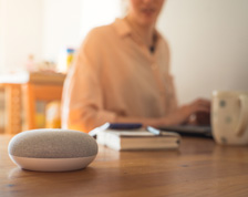 A smart speaker rests on a coffee table in a living room.