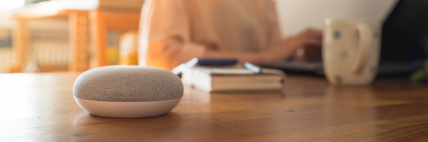 A smart speaker rests on a coffee table in a living room.