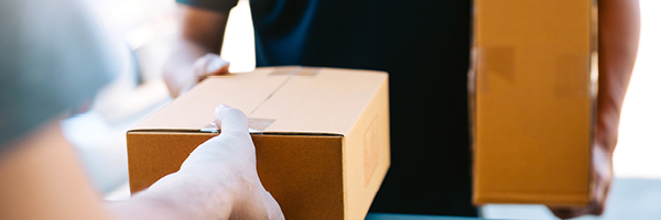 Delivery person hands a small package to an addressee.