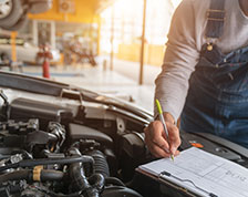 Auto mechanic inspects engine and marks checklist