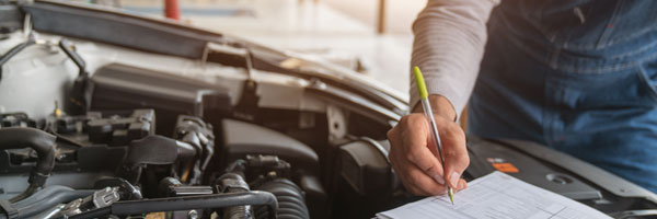 Auto mechanic inspects engine and marks checklist