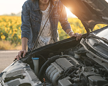 Woman experiences car trouble next to field of sunflowers