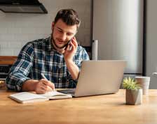 Young professional talks on phone while working from home