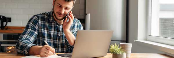 Young professional talks on phone while working from home