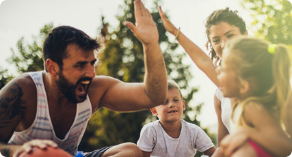 Father gives his daughter a high five while playing outside with family