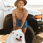 Young woman smiles and pets her dog in front of a white all-terrain vehicle