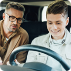 Father gives his teen driver instructions from the passenger seat of a car