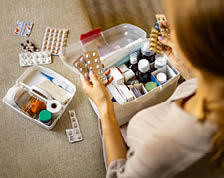 A woman sits with a fully stocked first aid kit complete with medications and bandages.