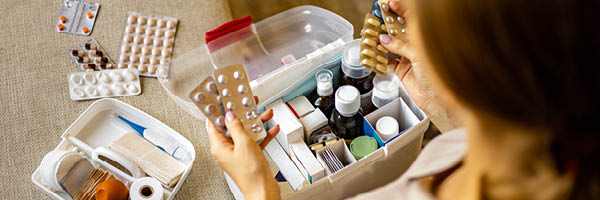 A woman sits with a fully stocked first aid kit complete with medications and bandages.