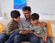 Father and sons look at tablet computer while at home
